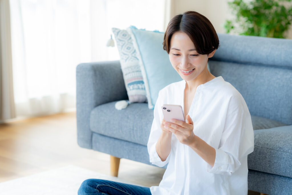 Middle-aged woman operating a smartphone in the room - 住宅AIコンシェルジュ