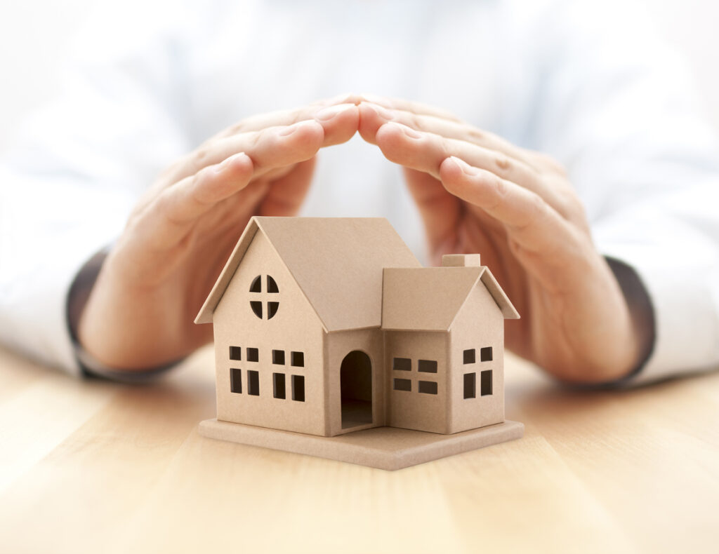 Property insurance House miniature covered by hands - 住宅AIコンシェルジュ